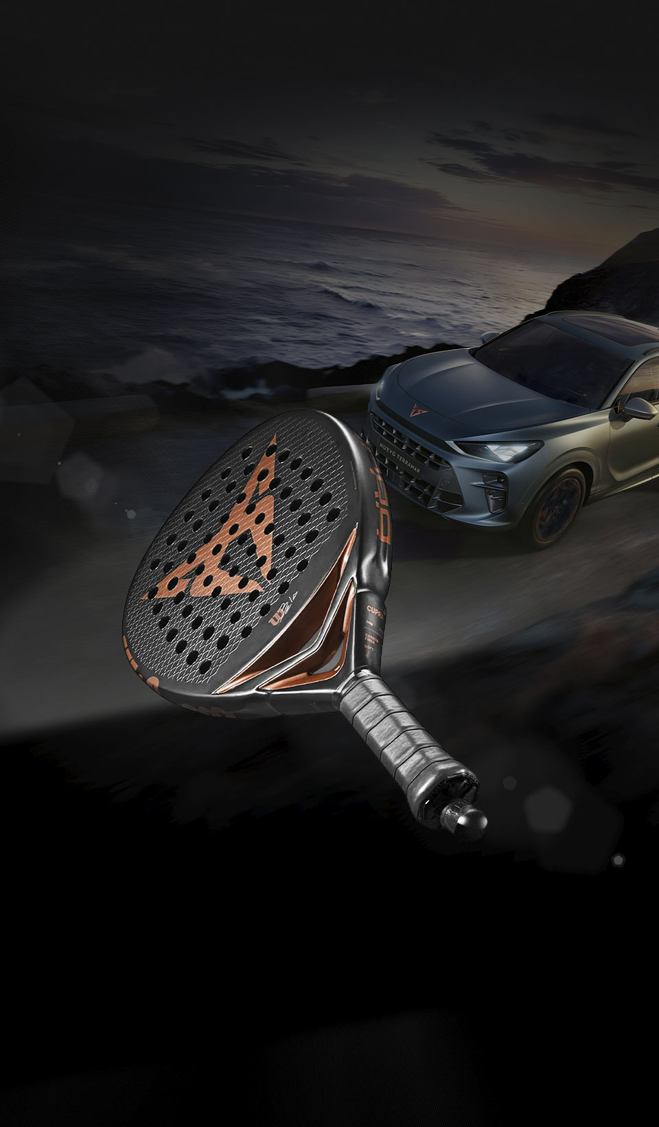 A front three-quarter view of a CUPRA Terramar parked in an empty outdoor parking lot at night. The vehicle is illuminated by a single overhead streetlamp, with mist or fog swirling around its front tires. The background features a dark silhouette of hills and distant city lights.